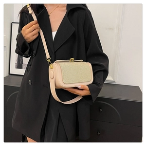 Gros plan d'un petit sac bandoulière avec rabat tissé doré et fermoir métallique