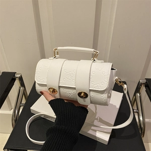 White Boston bag with vintage floral embossing and golden locks in a minimalist setting