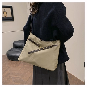 Detail of khaki nylon tote bag showing soft drape and leather straps on shoulder