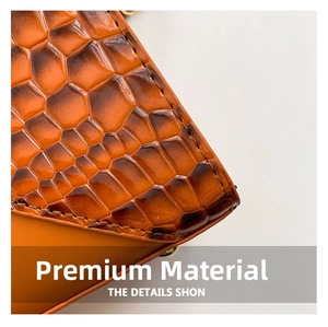 Close-up of orange-brown crocodile embossed leather bag with glossy finish and stitching