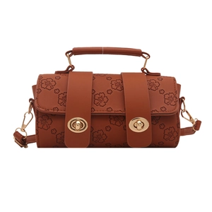 Caramel brown cylinder handbag with floral embossing and gold clasp closure on white background