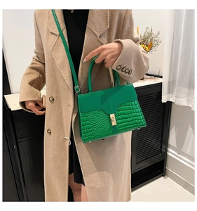 Detail of green leather shoulder bag with crocodile pattern and golden square clasp