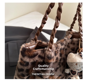 Macro shot of leopard faux fur tote featuring a braided brown leather handle and plush charm