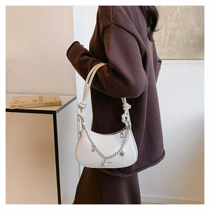 Detail of white crescent bag with silver chain, pearl charm, and knotted shoulder strap