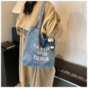 Détail du grand sac cabas en denim avec pendentif nuage et texte blanc sur le mannequin