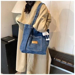 Détail d'un grand sac cabas en jean bleu avec écusson en cuir et pendentif nuage doux