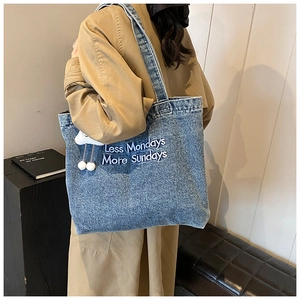 Détail du sac cabas en jean bleu avec broderie Less Mondays More Sundays et grigri nuage