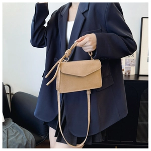 Detailansicht der khakifarbenen Umhängetasche mit Knotengriff auf blauem Blazer