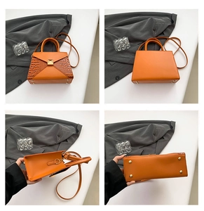 Detail view of orange crocodile texture bag with gold rivets and bottom studs