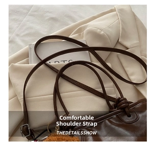 Close-up of adjustable thin straps and glossy dark brown leather on the bucket bag