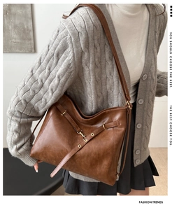 Brown leather tote bag styled with a gray cardigan and dark pleated skirt for daily wear