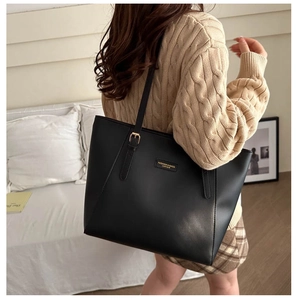 Vista laterale di una grande borsa tote in pelle PU nera con sottili tracolle e logo