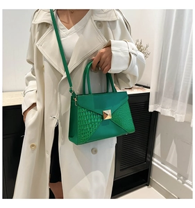 Detail of dark green crocodile texture stitching and gold rivet on a leather handbag