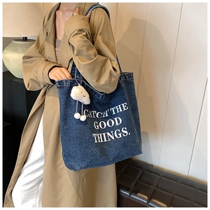Détail d'un grand sac cabas en jean avec slogan et breloque en forme de nuage blanc