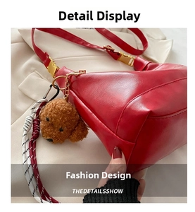 Detail of red crescent bag with glossy PU leather, golden buckle and plush dog charm
