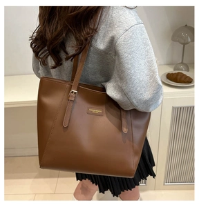 Detailed close-up of brown leather tote bag with fashion label and textured surface