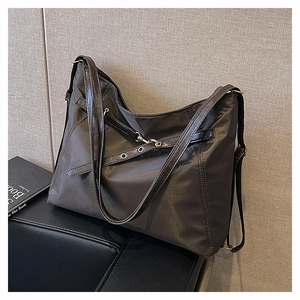 Detailed view of dark brown tote bag featuring nylon fabric and leather strap with grommets