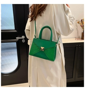 Model wearing a green crocodile texture handbag with gold buckle in minimalist setting