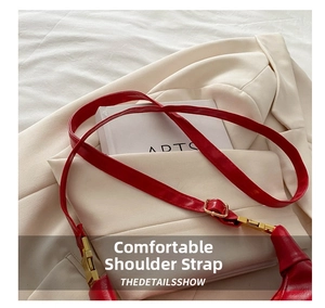 Close-up of red leather shoulder strap with adjustable gold buckle and fine stitching