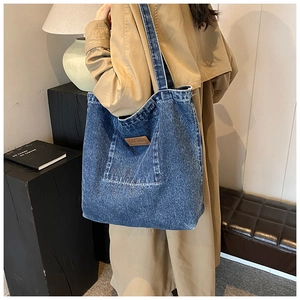 Détail du sac cabas en jean avec poche frontale et étiquette en cuir marron élégante
