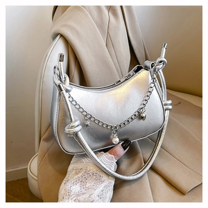 Detailed shot of silver dumpling bag featuring metallic texture, chains, and star charms
