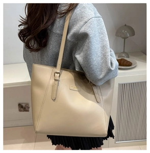 Beige oversized tote bag shown on shoulder in a minimalist modern lifestyle setting