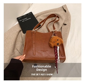 Dettaglio della borsa tote marrone vintage con tracolla regolabile e ciondolo a orsetto