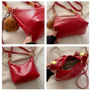 Detail view of red PU shoulder bag with teddy pendant and golden metal buckle