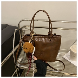Detail view of brown PU leather bucket bag with teddy dog charm and embossed logo lettering