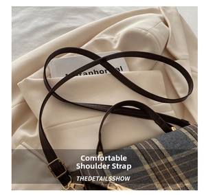 Detail of adjustable leather strap with golden metal buckle on retro plaid crossbody bag