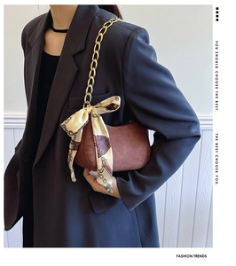 Dettaglio borsa hobo marrone scuro con catena dorata ed elegante sciarpa in seta decorativa