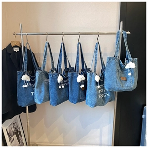 Detail van blauwe denim tote bags met witte letterprint en pluche wolkaccessoire