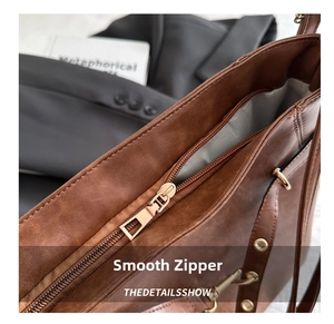 Detail view of smooth golden zipper and lychee textured brown leather on tote bag