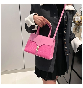 Detailed view of pink croc-effect handbag with gold metal clasp on a model