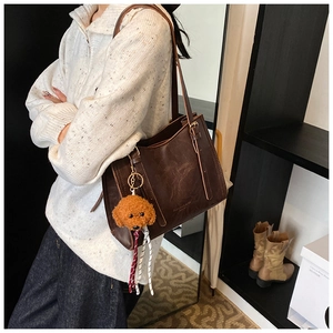 Dettaglio della grande borsa tote in pelle marrone con un simpatico ciondolo a barboncino
