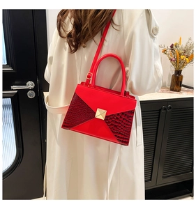 Detail of red crocodile texture handbag with golden square lock and detachable strap