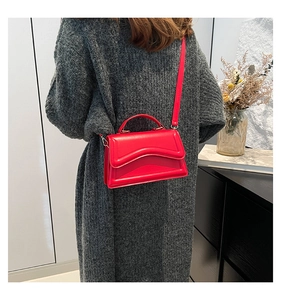 Detail der roten quadratischen Tasche mit Wellennähten über einem grauen Strickpullover