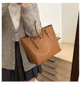 Close-up of caramel leather tote bag detail with adjustable metal buckle and smooth finish