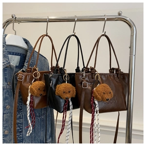 Detailed display of three vintage bucket bags with plush dog charms and woven straps