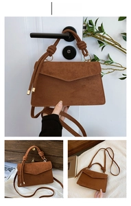 Detail der braunen Wildledertasche mit geknotetem Griff und goldener Metallverzierung
