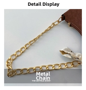 Dettaglio borsa scamosciata marrone con catena dorata e accessorio foulard in seta stampata