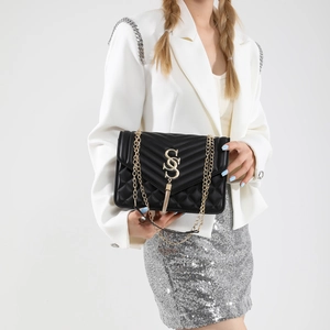 Close-up of black quilted leather bag with golden double-S logo and tassel details