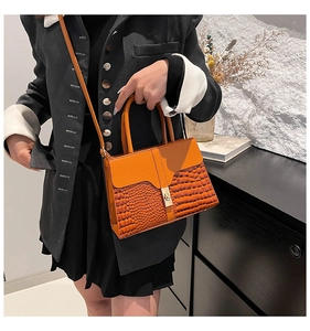 Detail of bright orange bag showing crocodile texture stitching and gold metal clasp