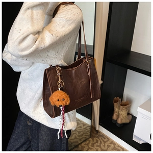 Dettaglio borsa tote in pelle marrone scuro con trama vintage e ciondolo a cane