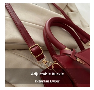 Detail view of burgundy leather handbag with adjustable strap and gold hardware
