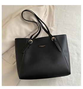 Dettaglio del logo dorato e spalline regolabili sulla borsa tote in pelle nera