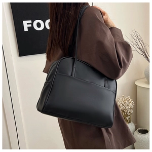 Détail du sac cabas minimaliste en cuir noir avec fines bandoulières pour le bureau
