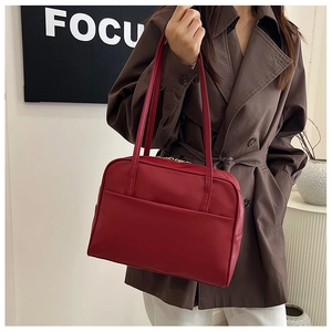 Détail du grand sac porté épaule rouge avec fermeture éclair dorée et texture cuir