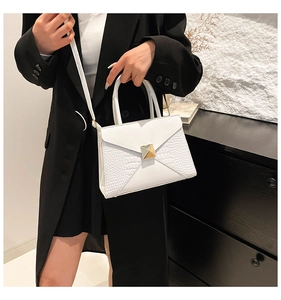 Detail of white crocodile pattern shoulder bag featuring golden metallic square lock