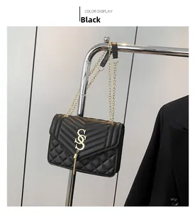 Detail of black quilted leather shoulder bag with gold V-pattern, logo and metal tassels
